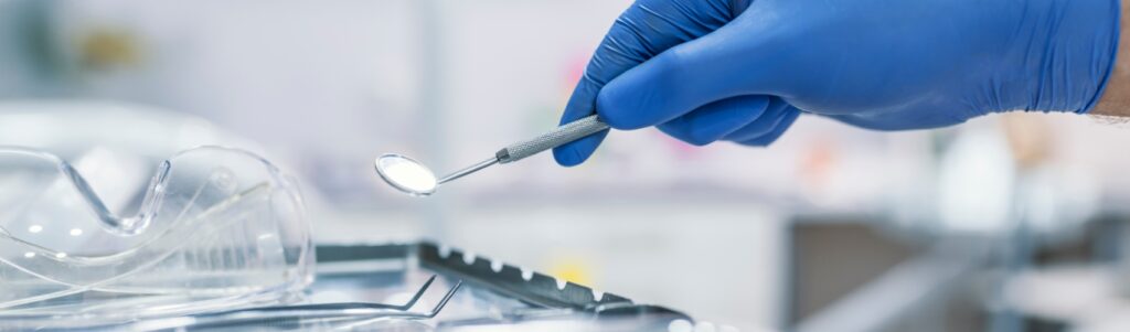 Close-up of a dental tool held by a gloved hand, representing precision in crafting a private equity investment thesis.